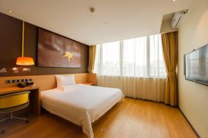 a bedroom with a bed and a desk and a tv at IU Hotel Kunming Jinma Bijifang Joy City in Kunming