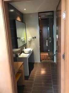 a bathroom with a sink and a mirror and a shower at IU Hotel Kunming Jinma Bijifang Joy City in Kunming