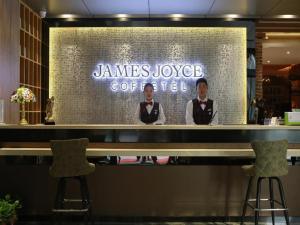 鄭州市にあるJames Joyce Coffetel Zhengzhou Aquarium Chenyan Flowerの二人の男が店のカウンターの後ろに立っている
