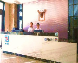 PAI Hotels·Yinchuan International Trade City في ينشوان: يجلس شخصان في مكتب مع الكمبيوتر المحمول