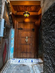 a wooden door with a light on top of it at Riad Fes Lile in Fez