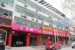 Un edificio en una calle con coches aparcados delante. en PAI Hotels·Zanhuang Bus Station, en Zanhuang