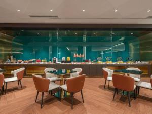 a restaurant with chairs and tables and a bar at Magnotel Business Jinan Zoo Wuyingshan North Road Flagship Hotel in Beiyuan