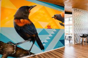 un mural de un pájaro sentado en una rama en Haka House Rotorua, en Rotorua