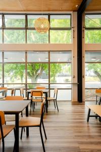 una cafetería con mesas, sillas y ventanas en Haka House Rotorua, en Rotorua