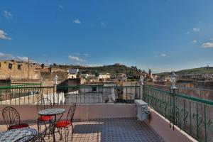 a balcony with tables and chairs and a view of a city at Riad Fes Lile in Fès