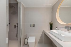 a bathroom with a sink and a toilet and a mirror at Mandarin apartments by halu! in Thessaloniki