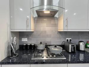 a kitchen with a stove with two pots on it at F4 Luxury Stays One bed apartment with Parking in Ilford