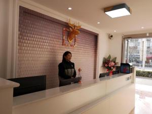 a woman standing at a counter in a lobby at PAI Hotels·Handan Lianfang Road Bus Station in Sucao