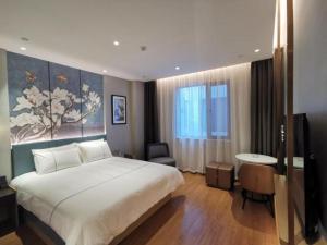 Un dormitorio con una gran cama blanca y una mesa en Magnotel Jining Jiaxiang Zengzi Avenue, en Jiaxiang