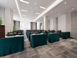 a conference room with green tables and chairs at Lavande Hotels·Mudanjiang People's Park in Mudanjiang