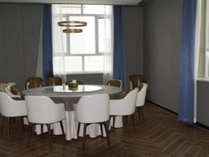 ein Esszimmer mit einem Tisch und weißen Stühlen in der Unterkunft Jinjiang Inn Select Jiuquan Wanda Plaza in Jiuquan