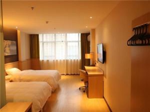 a hotel room with two beds and a desk and a television at IU Hotels·JI'an Railway Station in Ji'an