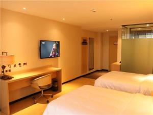 a hotel room with a desk and a tv on the wall at IU Hotels·JI'an Railway Station in Ji'an