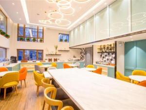 哈爾濱的住宿－Magnotel Harbin Songbei Wanda Wenlvcheng，一间设有五颜六色椅子和一张大长桌的自助餐厅