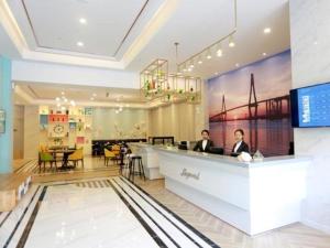 a lobby of a hotel with two people sitting at a counter at Magnotel Hotel Qionghai Wanquanhe Aihua Road in Qionghai