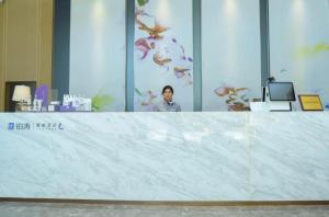 a woman standing behind a large white counter in a room at Lavande Hotel Taizhou Medicine Market People's Square in Taizhou