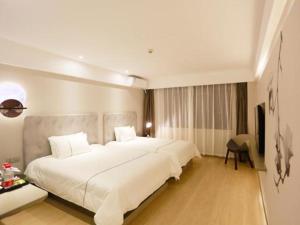 a large white bed in a hotel room at Magnotel Hotel Qionghai Wanquanhe Aihua Road in Qionghai