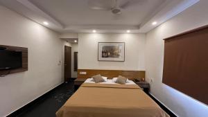 a bedroom with two beds and a flat screen tv at Wise Owl Comfotel in Kolkata