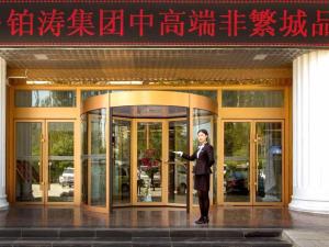 Um homem de fato à porta de um edifício. em Chonpines Hotels·XiNing Qingzang Building em Xining