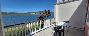 a balcony with two chairs and a table and water at Casa de Pueblo Knysna Views! in Knysna