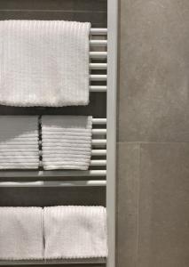 un mucchio di asciugamani bianchi su un appendiabiti in bagno di Palazzo 7 a Domodossola