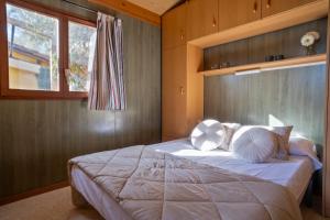 a bedroom with a bed with white pillows and a window at Camping Castell Mar in Empuriabrava
