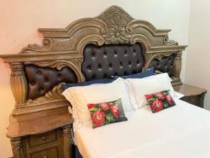 a bed with a large wooden headboard and two pillows at Afrite Rooms Goodwood in Cape Town