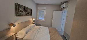 um pequeno quarto com uma cama e uma janela em APARTAMENTOS TURISTICOS LOS ROQUES em Cáceres