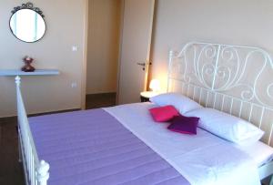 a bedroom with a white bed with purple pillows and a mirror at Porto Katsiki Blu in Athani
