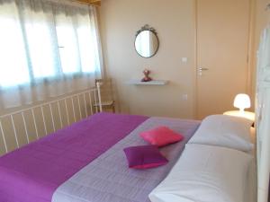 a bedroom with a purple and white bed with two pillows at Porto Katsiki Blu in Athani