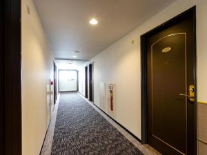 un pasillo con una puerta negra y una alfombra en OYO Sun Hotel Kokubu Kagoshima en Kirishima