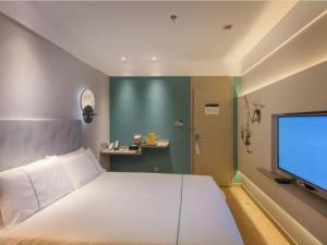 a bedroom with a large bed and a flat screen tv at Magnotel Hotel Shiyan Wuyan Pedestrian Street in Shiyan