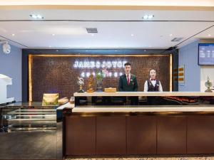 郑州James Joyce Coffetel Zhengzhou CBD Exhibition Center Provincial People's Hospital的两个男人站在酒店大堂柜台后面
