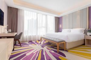 北京市にあるLavande Hotel·Beijing Capital Airport Xiedaoの大きなベッドとデスクが備わるホテルルームです。