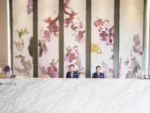 two men standing behind a table with a wall with flowers at Lavande Hotel·Tianmen Xincheng in Tianmen