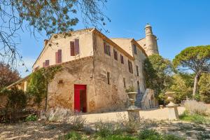 um antigo edifício de pedra com uma porta vermelha e um farol em Château de Sauvian em Sauvian