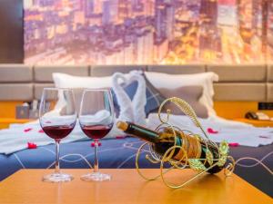 two glasses of wine on a table next to a bed at Chonpines Hotel Guangzhou Sunac Cultural and Tourism City Shiling in Huadu