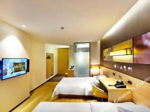 a hotel room with two beds and a tv at IU Hotel·Tianjin Binhai New District Yanghuo Market in Binhai