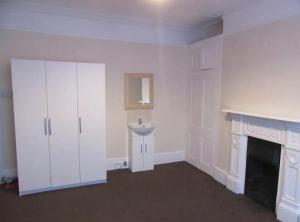 um quarto branco com um lavatório e uma lareira em Durley house em Alphington