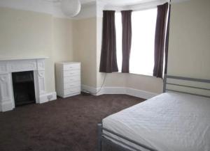 a white bedroom with a bed and a fireplace at Durley house in Alphington