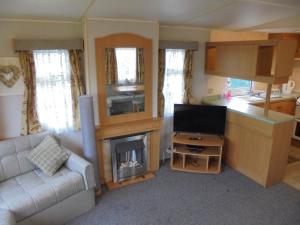 a small living room with a couch and a television at 8 Berth Northshore Skegness The Cottage Panel heated in Lincolnshire +16 photos