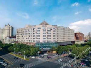 a large white building in a city with a parking lot at James Joyce Coffetel Tianjin Development 3rd Street MSD in Binhai
