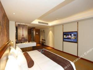 a bedroom with a large bed with a tv on the wall at James Joyce Coffetel Tianjin Development 3rd Street MSD in Binhai