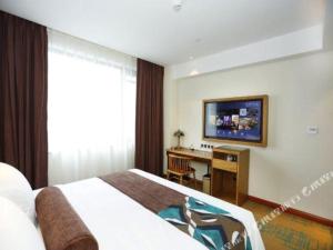 a bedroom with a bed and a desk and a television at James Joyce Coffetel Tianjin Development 3rd Street MSD in Binhai
