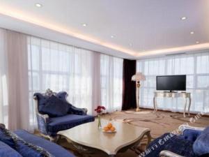 Vienna Hotel Tongliao Ke'erqin في تونغلياو: غرفة معيشة مع أثاث أزرق وتلفزيون