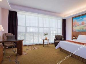 ein Hotelzimmer mit einem Bett, einem Schreibtisch und einem Fenster in der Unterkunft Vienna Hotel Tongliao Ke'erqin in Tongliao