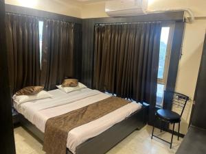 a bedroom with a bed and a window with curtains at Hotel Apple Inn in Ahmedabad