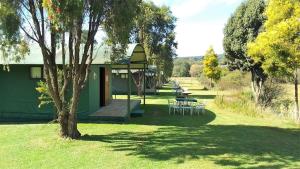 a green building with tables and chairs in the grass at Sabie River Camp in Sabie