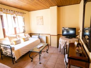 um pequeno quarto com uma cama e uma televisão em Posada el Campanario em Rascafría
